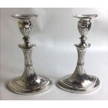 A PAIR OF SILVER PLATED CANDLESTICKS With reeded decoration over a shaped oval base. (h 23cm)