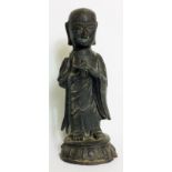 A CHINESE BRONZE STANDING BUDDHA With long flowing robes and a dark patinated finish. (approx 20cm)