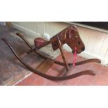AN EARLY 20TH CENTURY MAHOGANY AND STAINED PINE ROCKING HORSE With red leather seat and painted