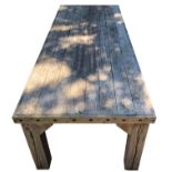 A LARGE RUSTIC RECLAIMED WOODEN GARDEN TABLE The plank top over large square section legs. (l