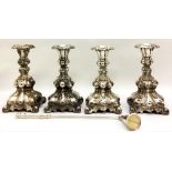 A SET OF FOUR SILVER PLATED ROCOCO STYLE CANDLESTICKS Having tapering flutes and square bases,