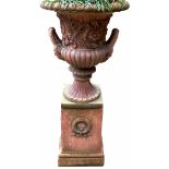 AN 18TH CENTURY DESIGN FAUX TERRACOTTA TWO HANDLED URN ON STAND Decorated with foliage and facial