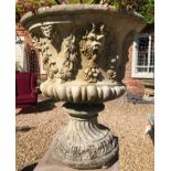 A PAIR OF RECONSTITUTED STONE URNS Cast with horned masks and grape vines, raised on socle bases. (
