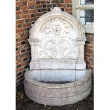 A RECONSTITUTED STONE FOUNTAIN Cast with facial mask and foliage above a semi-circular font. (