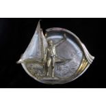 AN EARLY 20TH CENTURY SILVER PLATED PEWTER DISH Embossed with a gentleman stood on a quayside,