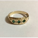 A VINTAGE 9CT GOLD AND EMERALD THREE STONE RING Having three round cut emeralds interspersed with