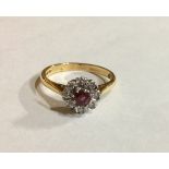 A VINTAGE 18CT GOLD, RUBY AND DIAMOND DAISY CLUSTER RING Having a single round cut ruby surrounded