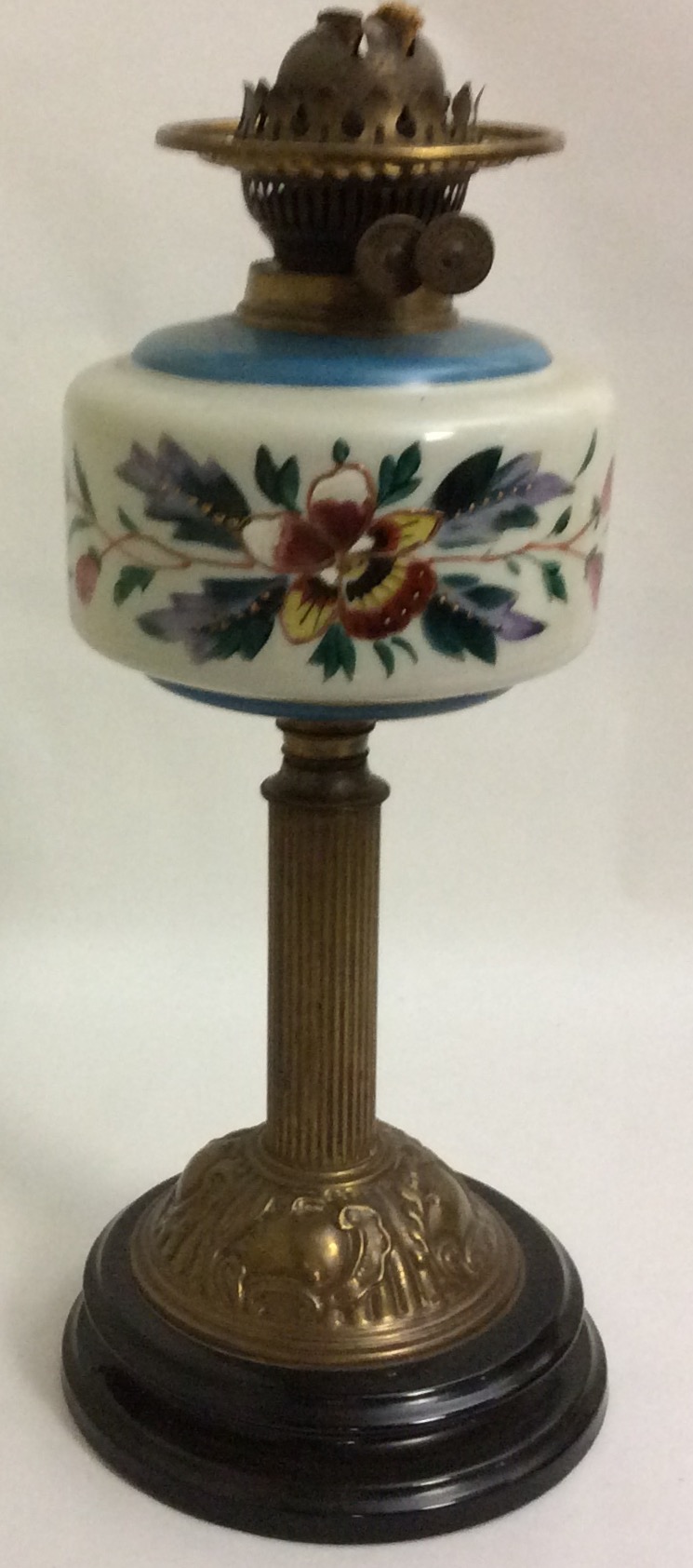 AN EDWARDIAN BRASS AND COLOURED GLASS OIL LAMP The spherical well hand painted with floral