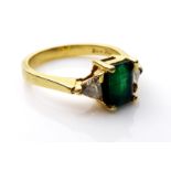 AN 18CT GOLD, EMERALD AND DIAMOND RING The single emerald cut stone flanked by pear cut diamonds (