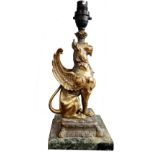 A 19TH CENTURY GILT METAL STATUE OF A WINGED LION CONVERTED TO A LAMP On a marble base. (35cm)