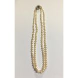 A VINTAGE DOUBLE STRAND PEARL NECKLACE The 9ct gold clasp set with a single round cut garnet