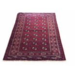 AN PERSIAN BOKHARA WOOLLEN RUG The red central field having gul motifs, edged with a running border.