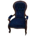A VICTORIAN MAHOGANY SPOON BACK OPEN ARMCHAIR Upholstered in a button back blue velvet, castors