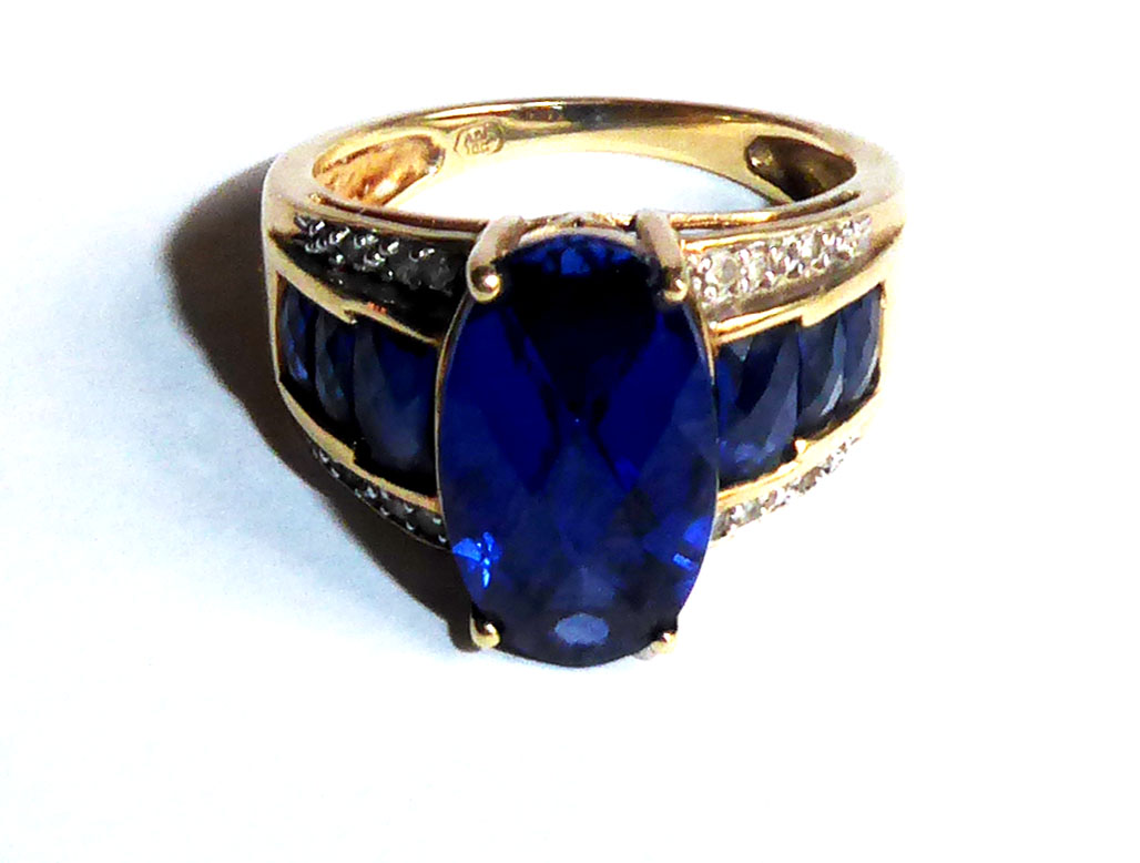 A VINTAGE AMERICAN 10CT GOLD, SAPPHIRE AND DIAMOND RING Having a faceted oval cut sapphire flanked