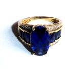 A VINTAGE AMERICAN 10CT GOLD, SAPPHIRE AND DIAMOND RING Having a faceted oval cut sapphire flanked