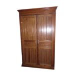 A VICTORIAN PITCH PINE ARMOIRE With panelled doors raised on bun feet. (w 140cm d 54cm x h 232cm)