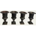 A SET OF FOUR REGENCY DESIGN IRON CAMPANA URNS The everted rims with relief decoration, raised on