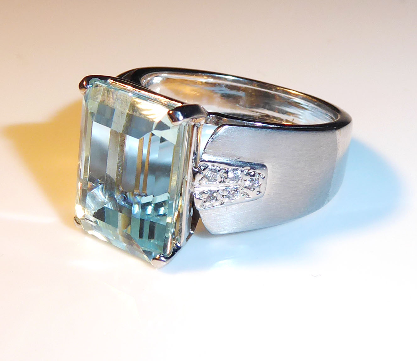 A 10CT WHITE GOLD, AQUAMARINE AND DIAMOND RING Cushion cut aquamarine flanked by diamonds (size V).