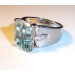A 10CT WHITE GOLD, AQUAMARINE AND DIAMOND RING Cushion cut aquamarine flanked by diamonds (size V).