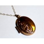 A VINTAGE 9CT GOLD OVAL LOCKET AND NECKLACE Having a scrolled floral design and suspended from a
