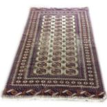 A PERSIAN BOKHARA WOOLLEN RUG The beige ground central field having gul motifs, edged with a