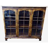 AN EDWARDIAN WALNUT BOOKCASE The three doors with astragal glazed panels, raised on shaped bracket