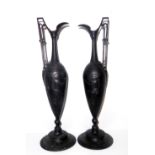 A PAIR OF CAST IRON CLASSICAL STYLE EWERS Having a single handle and embossed decoration of