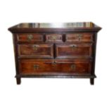 A 17TH CENTURY OAK CHEST Fitted with an arrangement of short and long drawers, raised on stile legs.