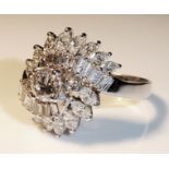 A WHITE METAL AND DIAMOND CLUSTER RING Three round cut diamonds flanked by baguette and oval cut