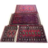 A COLLECTION OF FOUR PERSIAN WOOLLEN RUGS Comprising two Bokhara rugs with red grounds and gul
