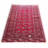 AN PERSIAN BOKHARA WOOLLEN RUG The red central field having gul motifs, edged with a running border.