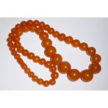 AN AMBER NECKLACE Comprising graduated beads. (approx l 64cm)
