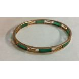 AN EARLY 20TH CENTURY 9CT GOLD AND JADE SLAVE BANGLE Having curved jade segments interspersed with