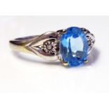 A 9CT WHITE GOLD, TOPAZ AND DIAMOND RING Having a single oval cut stone flanked with diamonds (