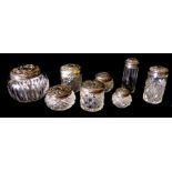 A COLLECTION OF EIGHT EDWARDIAN SILVER AND CUT GLASS TRINKET BOTTLES Each having spherical