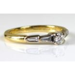 AN 18CT GOLD AND DIAMOND STEP CUT RING Having a round cut diamond flanked by tapering baguettes (