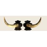 A PAIR OF WALL HANGING COW HORNS Mounted on carved cartouche panels.