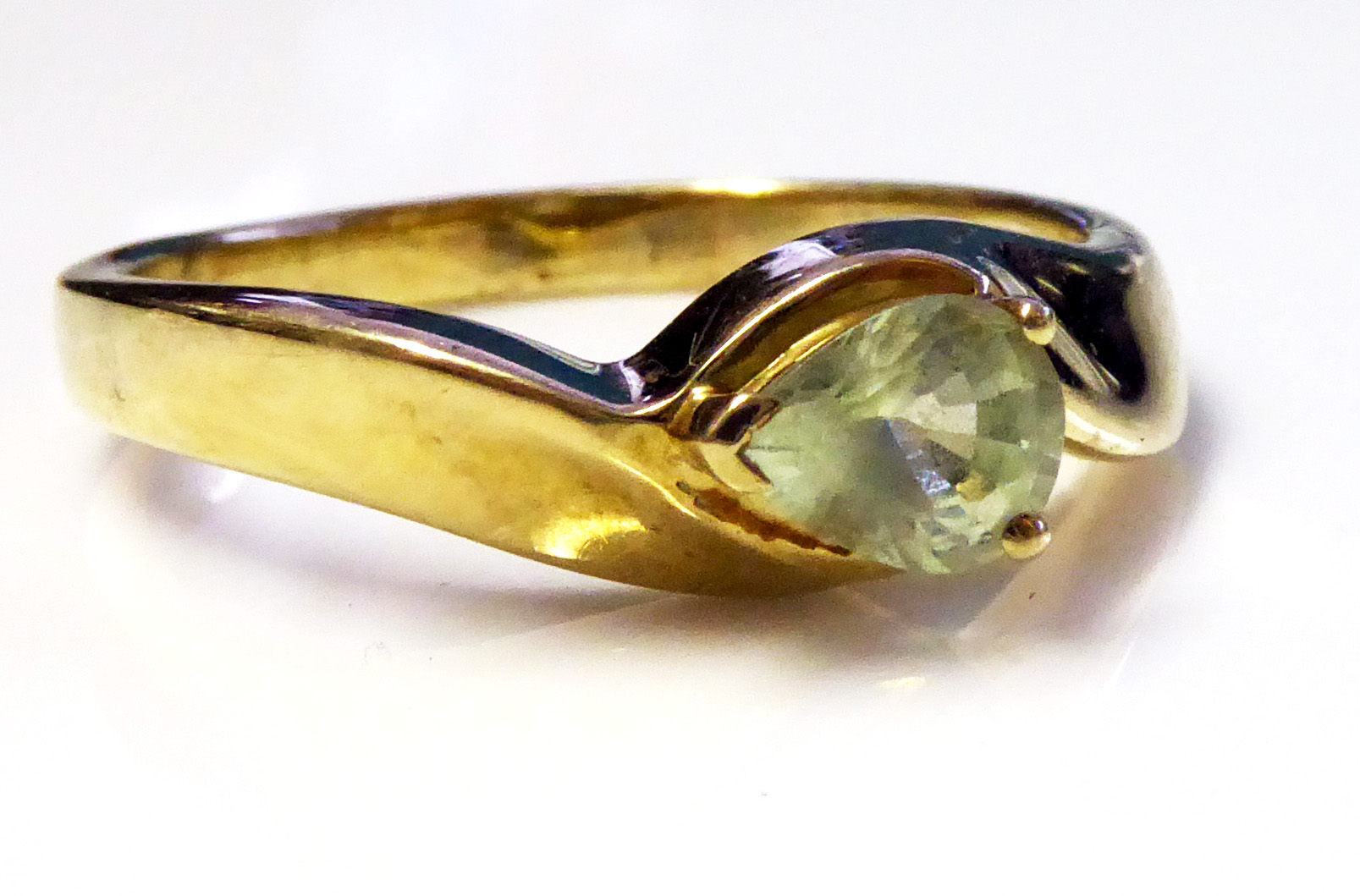 A 9CT GOLD AND PERIDOT RING Having a single pear cut stone set in a half twist mount (size O).