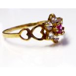 A VINTAGE 9CT GOLD, RUBY AND WHITE SAPPHIRE RING The single ruby edged with sapphires and held in