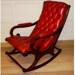 A VINTAGE MAHOGANY AND RED LEATHER ROCKING CHAIR Having elongated scrolled arms and button back