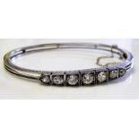 AN ANTIQUE 18CT WHITE GOLD AND DIAMOND BANGLE Set with graduating diamonds, contained in original