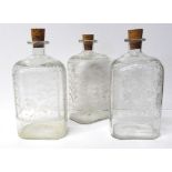 A SET OF THREE GEORGE III ETCHED GLASS DECANTERS Of shouldered form with foliate decoration and cork