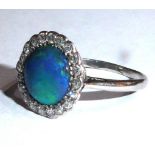 A VINTAGE WHITE METAL, OPAL AND DIAMOND RING The circular cabochon cut stone edged with diamonds (