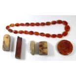 A CHINESE ORANGE AGATE ROUNDEL Carved with a pierced dragon, together with a hardstone necklace with