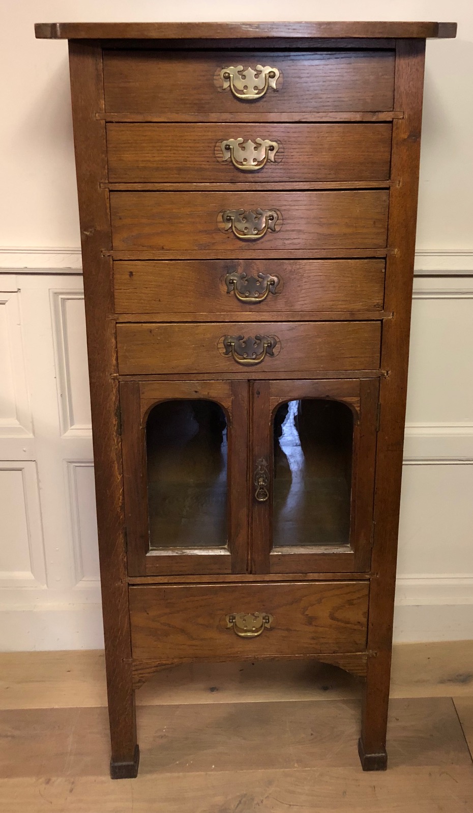 A 19TH CENTURY SOLID OAK PEDESTAL CHEST Having an arrangement of six drawers and a pair of glazed