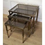 MANNER OF MAISON JANSEN, A 20TH CENTURY BRASS AND GLASS NEST OF THREE TABLES Raised on reeded