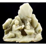 AN 18TH CENTURY GREEN CHINESE JADE FIGURAL CARVING OF A SCHOLAR Seated beside a fire beneath an