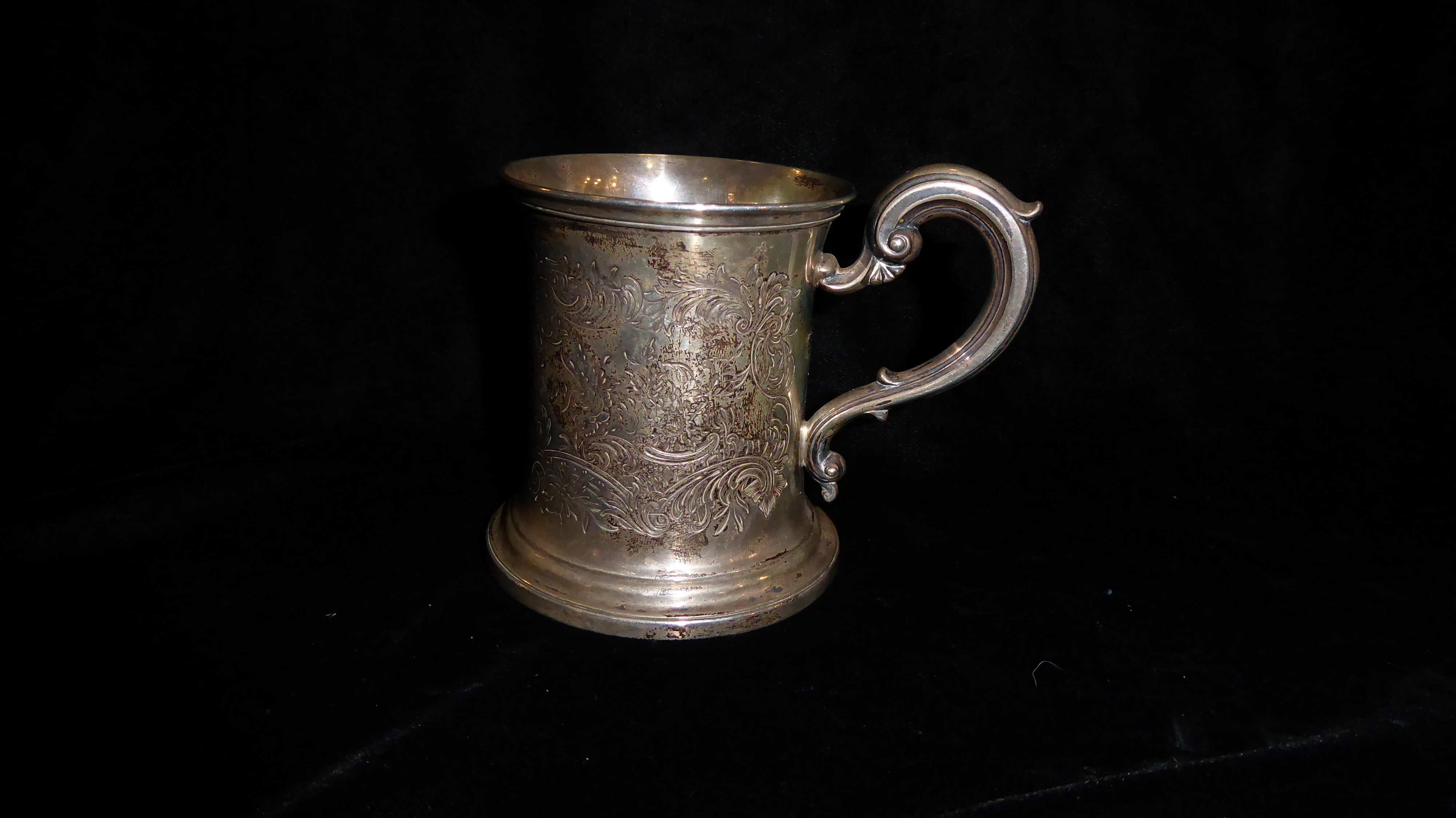 A VICTORIAN SILVER CHRISTENING MUG Having a scrolled handle and finely engraved decoration,