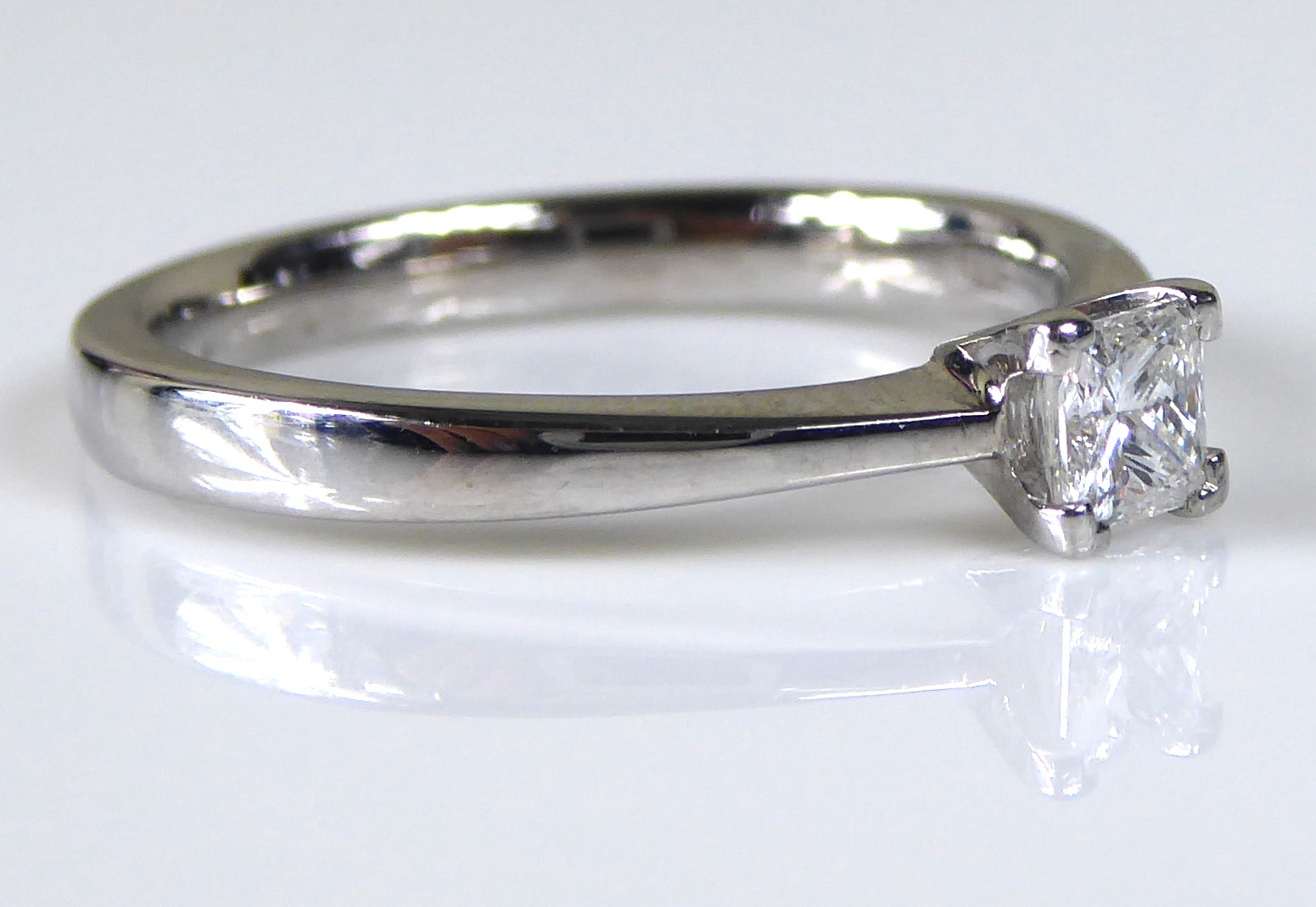 AN 18CT WHITE GOLD AND DIAMOND SOLITAIRE RING Set with a Princess cut stone held in a raised