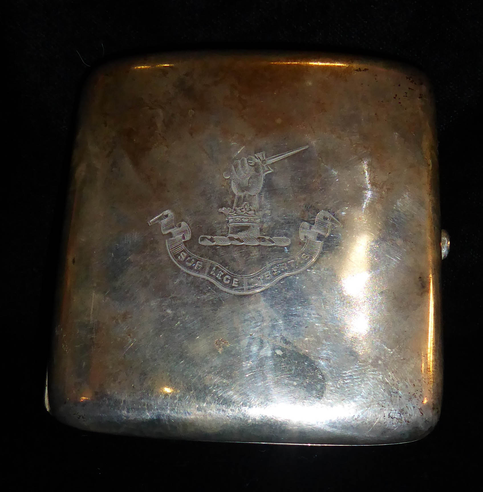 AN EDWARDIAN SILVER CIGARETTE CASE Of plain form, bearing an engraved family crest of a hand with